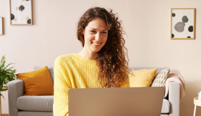 Donna sorridente che utilizza un computer portatile e avvia Norton Safe Search.